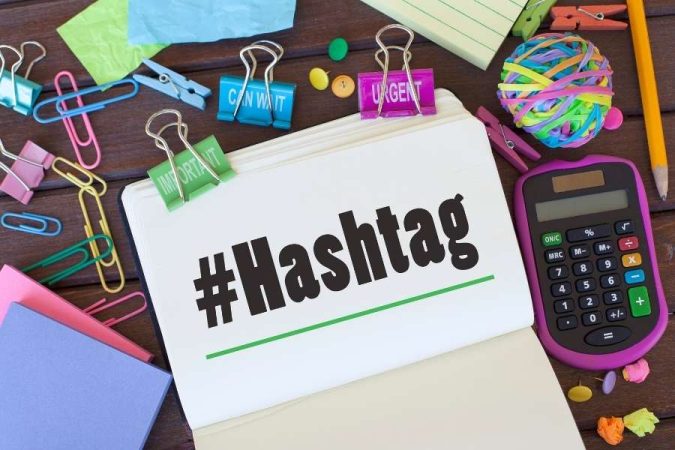 Carnet de notes avec le mot hashtag écrit dessus entouré de fournitures de bureau.