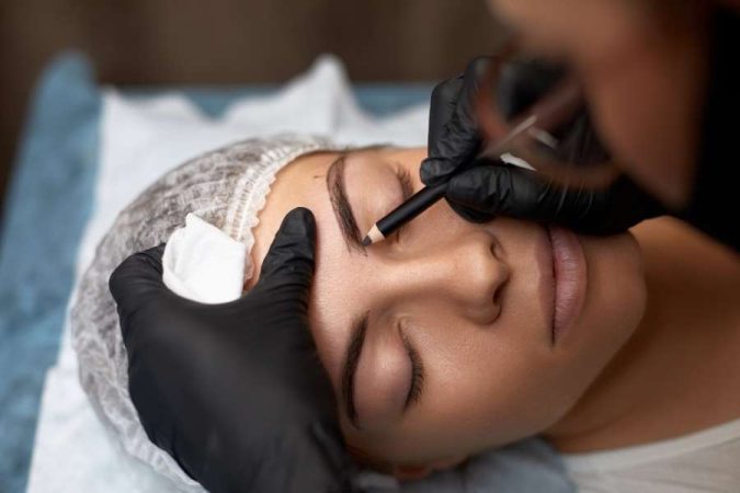 Une esthéticienne trace les sourcils pour sublimer ses cils et son regard.