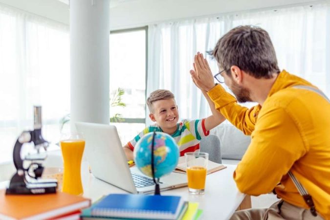 Un jeune garçon et son père se font un tape-main joyeux après une session d'apprentissage pour encourager l'autonomie.